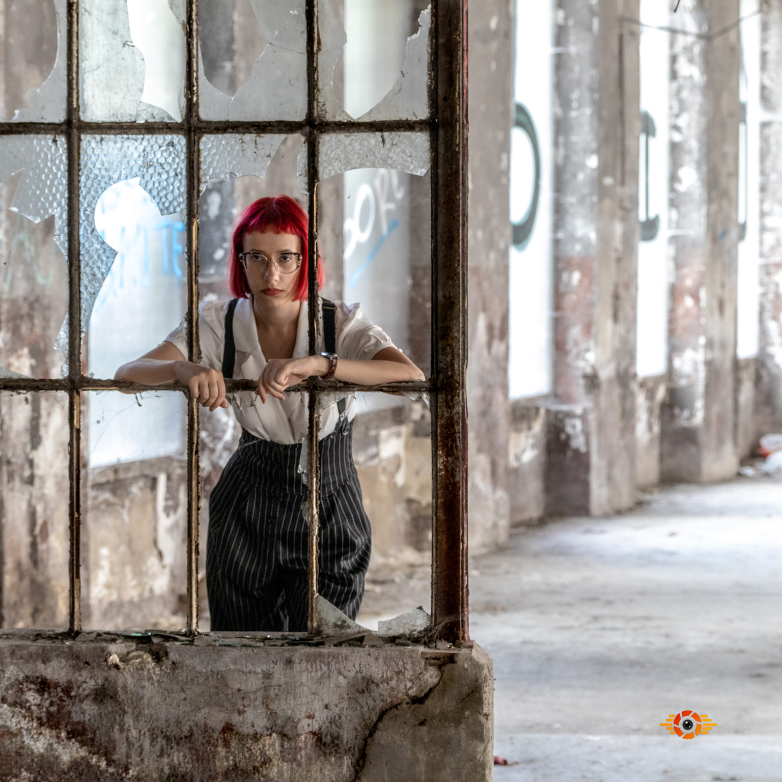 une femme se tiend devant une fenetre cassée dans un environnement urbex