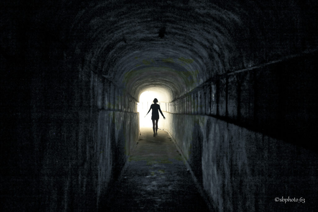 photo en noir et blanc prise dans un bunker, une silhouette part vers ou revient de la lumière